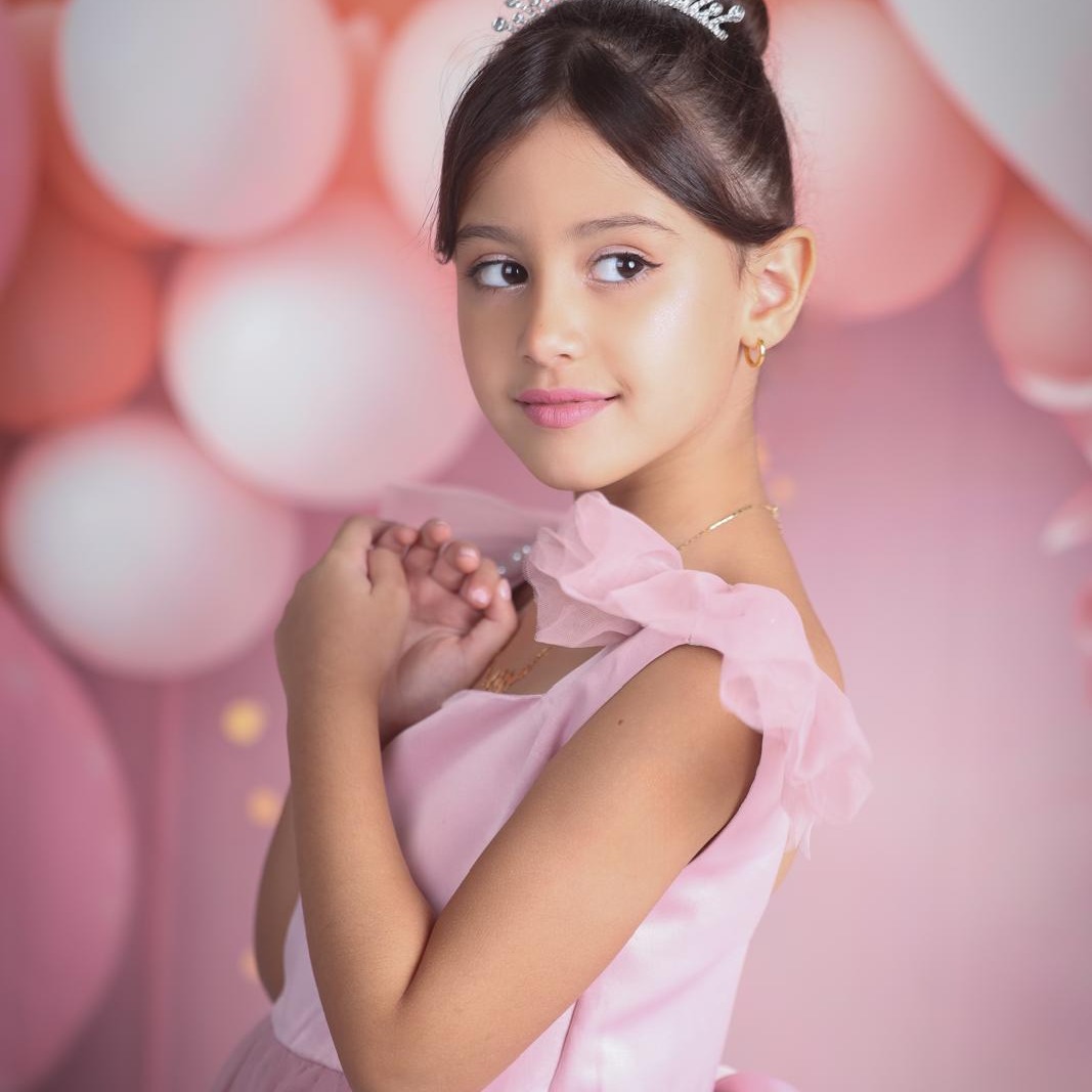 A young model in a pink dress looking to the side.
