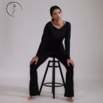 Woman in black outfit sitting on a stool.