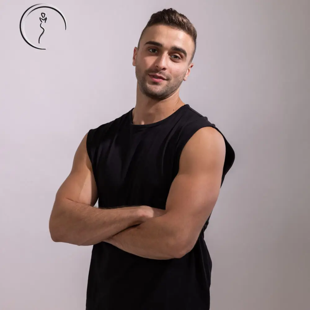 Male model in Kuwait with arms crossed, smiling, wearing a black sleeveless shirt.