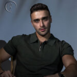 Male model in Kuwait with a serious expression, wearing a dark green polo shirt with a zipper.