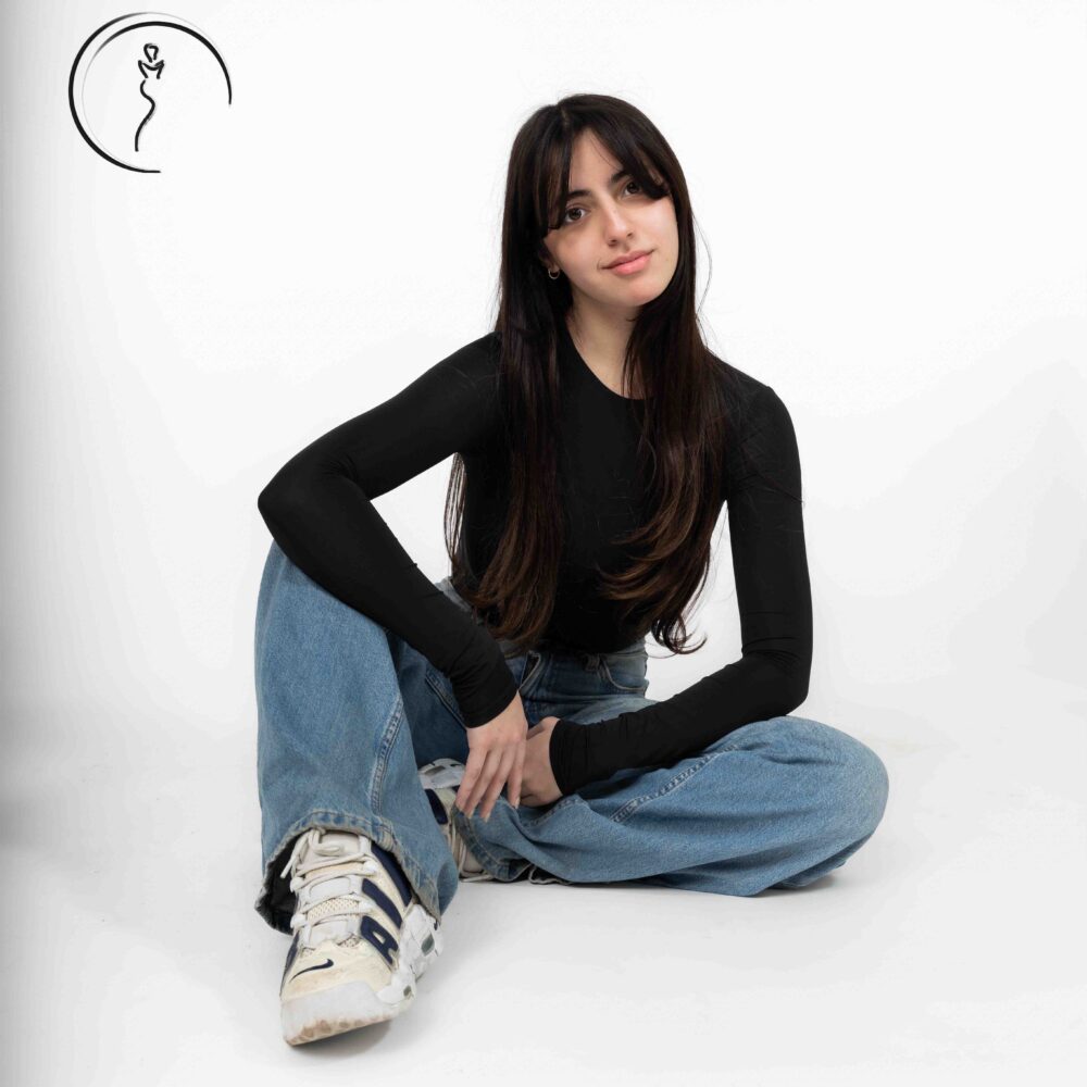 Female model in black top and wide-leg jeans posing in studio