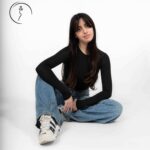 Female model in black top and wide-leg jeans posing in studio