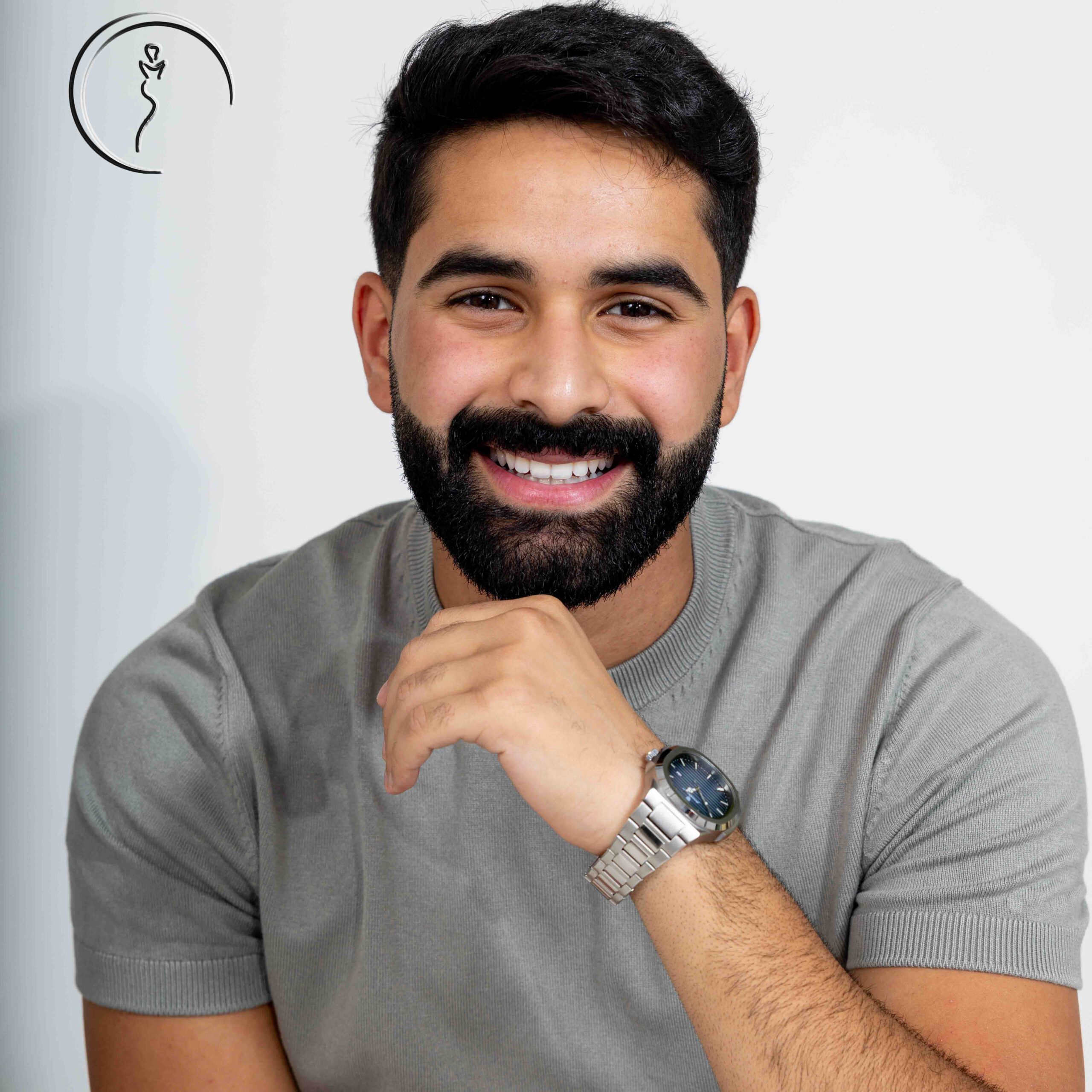 Male model in gray T-shirt and jeans checking time in studio