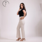 Woman in black top and white pants posing.