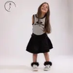 Smiling child model from Kuwait in monochrome outfit and fuzzy sneakers