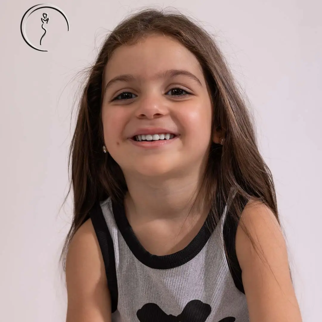 Young Kuwaiti female model in a black skirt and grey top, smiling confidently during a studio shoot.