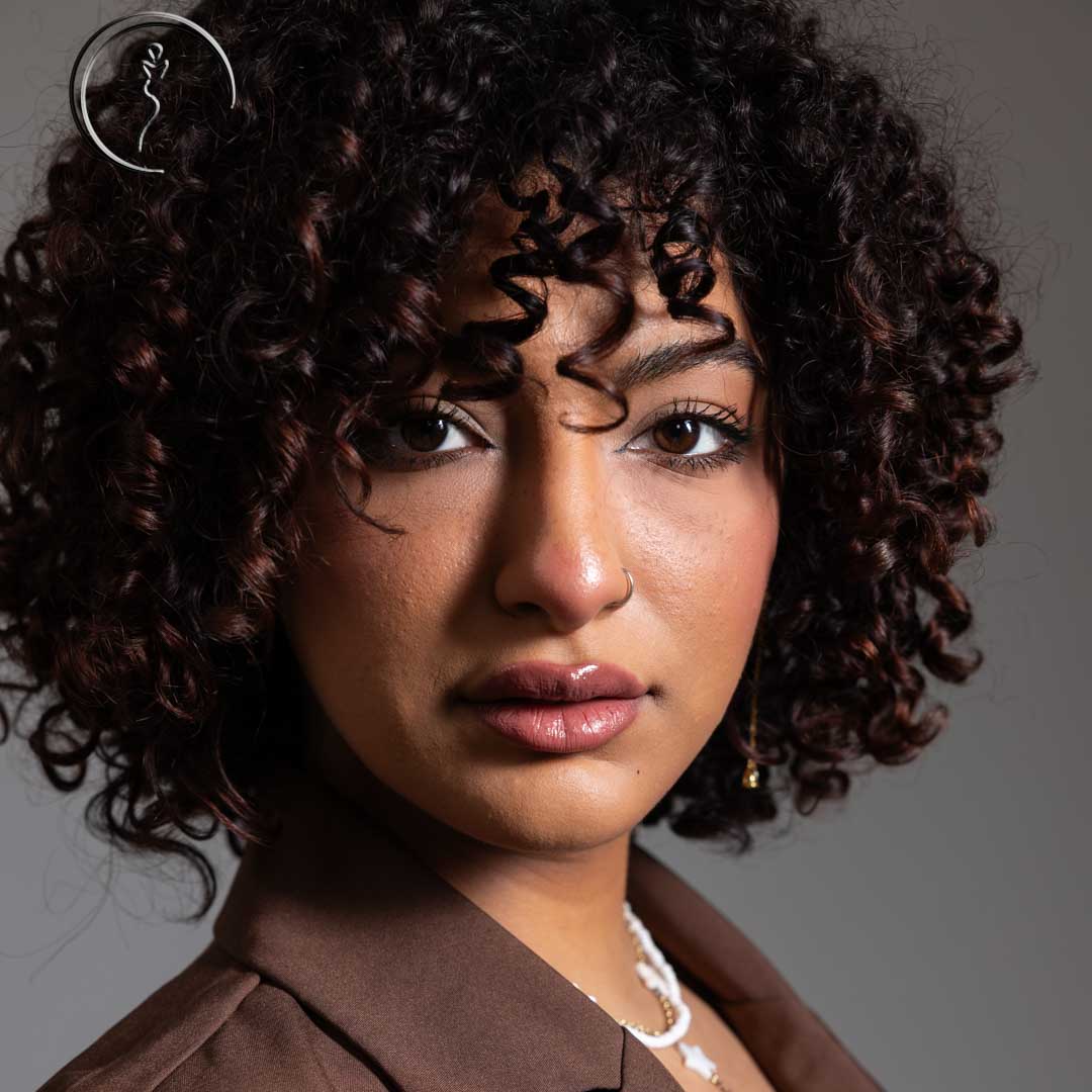 Woman with curly hair looking at the camera.