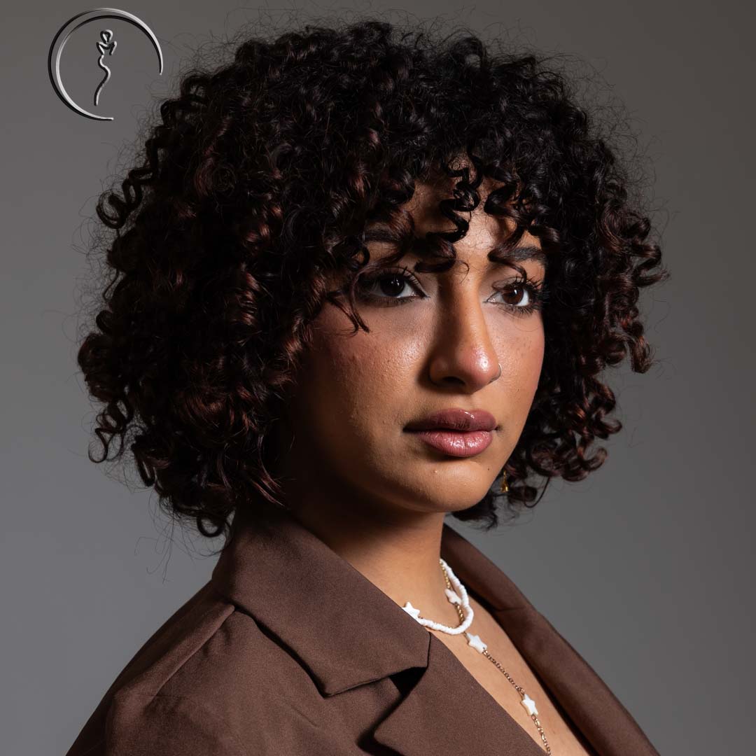 Woman in a brown jacket with a serious look.
