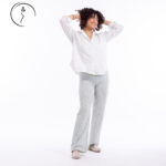 Woman standing casually with hands in hair.