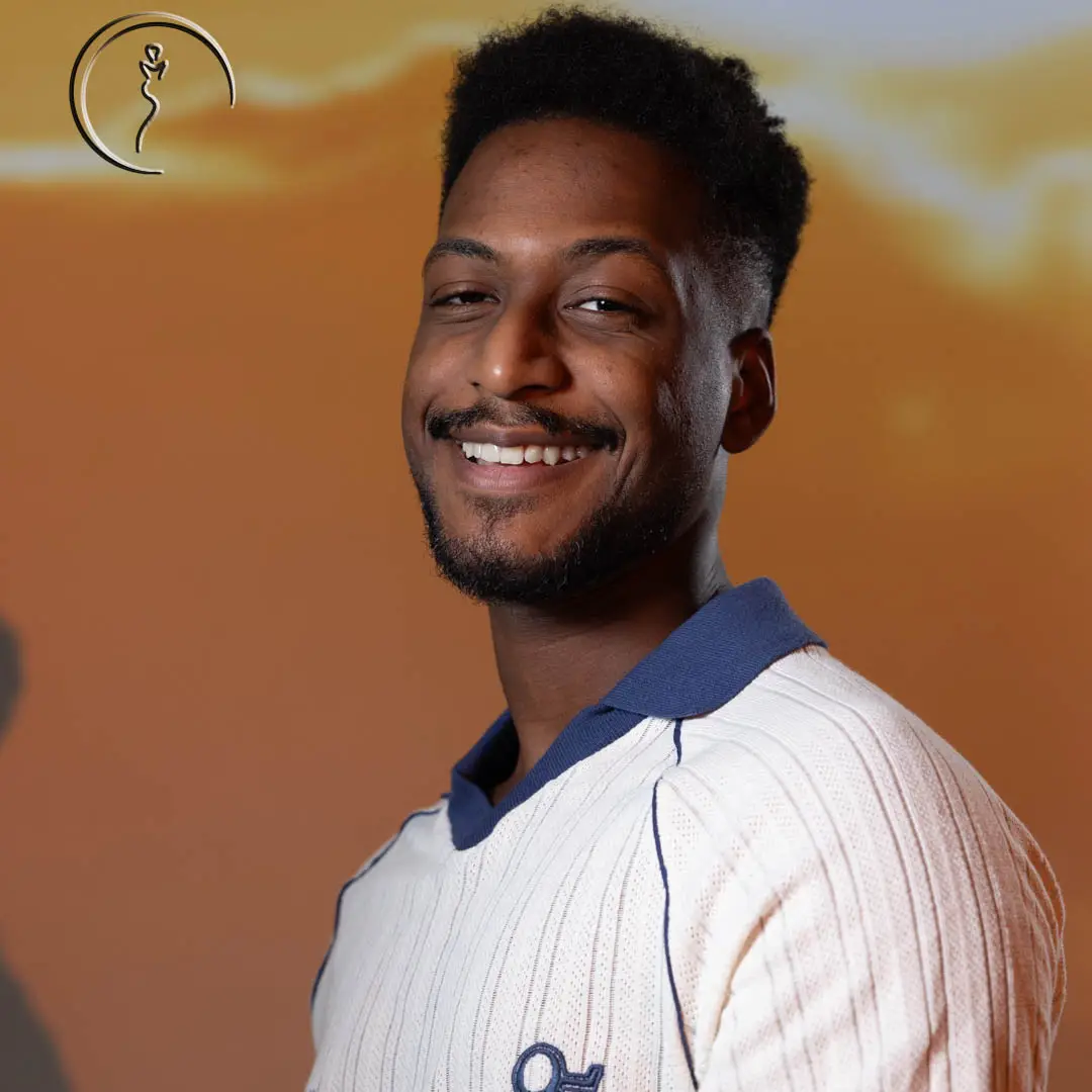 Young man smiling in front of orange sky projection.