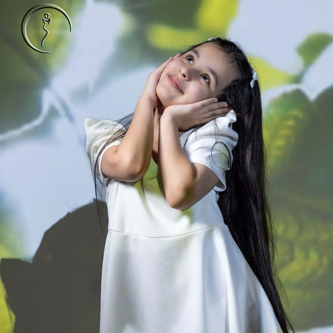 Confident young girl posing in a white dress