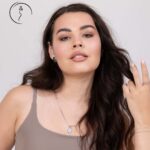 Beautiful woman with natural makeup wearing a beige top and silver jewelry