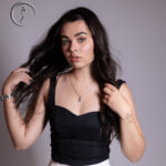Elegant woman in black top with wavy hair posing indoors