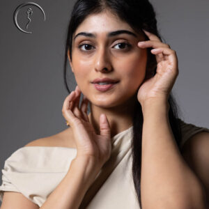 A close-up portrait of an Indian model with her hands touching her face