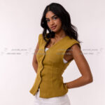 Female model, smiling, green button-up top, hands behind back.