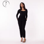 A full-body shot of a female model in black pants with her hands in her pockets.