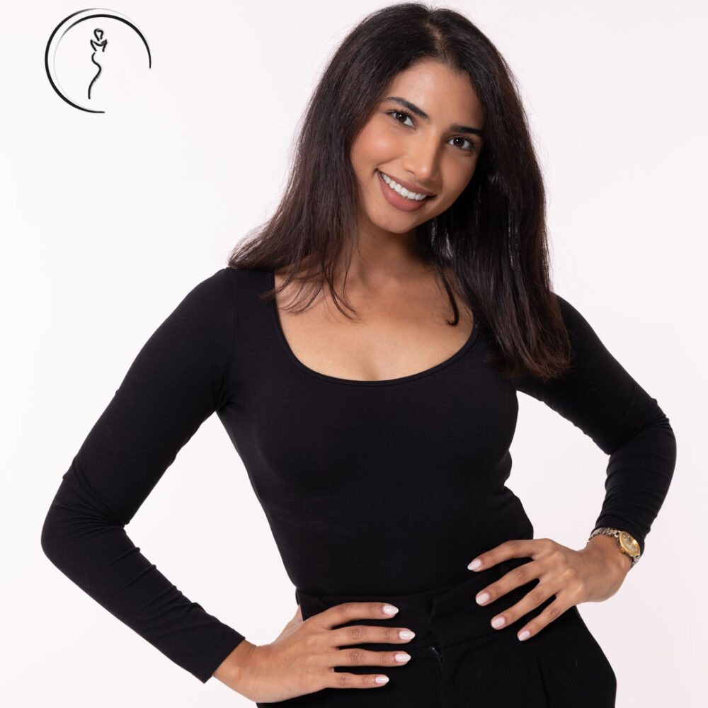 A female model in a black shirt smiling, with her hands on her hips.
