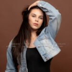 New model in Kuwait in a denim jacket, hand in her hair, fashion portrait shoot on a brown backdrop – female model 690