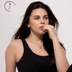 Female model in Kuwait in a black tank top, hand at her chin, clean white studio portrait – Model 690