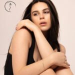 New model in Kuwait in a black tank top, arms wrapped around her knees, soft studio portrait – female model 690